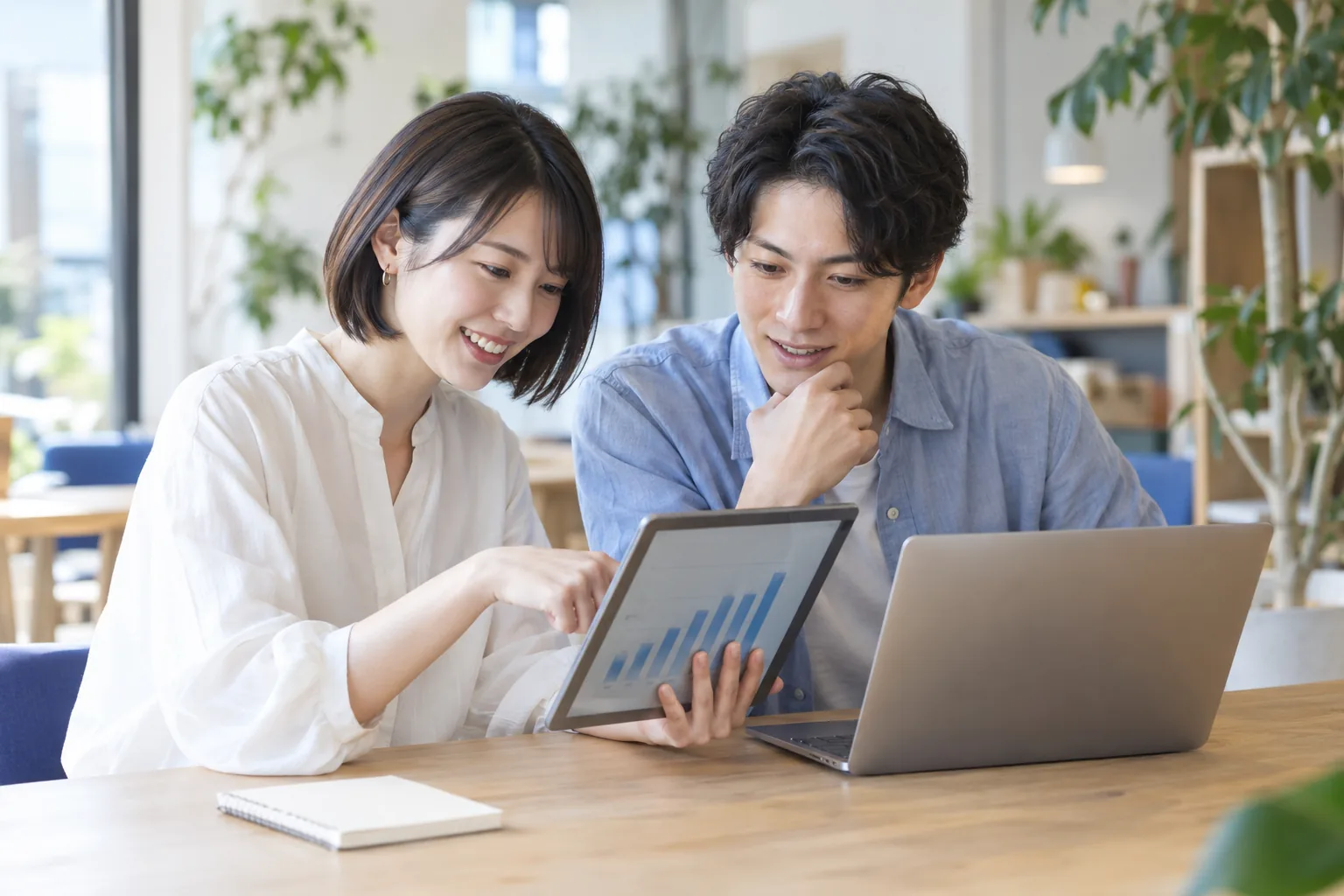 タブレットのグラフを確認し、データの根拠を検討する若いリサーチチーム